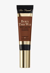 Tube marron de fond de teint mat huileux contrôle de Too Faced Born This Way avec des accents dorés, présentant un capuchon noir et un étiquetage clair à l'avant.