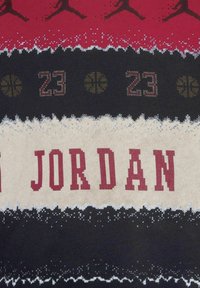Maglione lavorato a maglia con schema di colori rosso, nero e beige. Testo "JORDAN" in rosso audace, con motivi di pallacanestro e accenti con il numero "23".