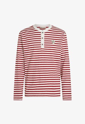 Rød- og hvidstribet langærmet skjorte med en ensfarvet knapliste, der har en rund halsudskæring og et rundt logoemblem på brystet.