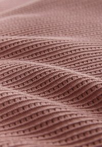 Tissu tricoté rose pâle avec une texture côtelée ondulée créant de petites lignes horizontales en relief et en creux.