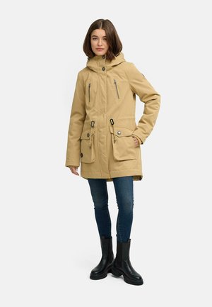 Beige parka jacket with a hood, multiple pockets, and zippers. Made from textured material, featuring black hardware and a relaxed fit.