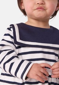 T-shirt en tricot rayé blanc et marine avec un col marin. Il dispose de manches longues avec des poignets contrastants. Texture douce, design simple.