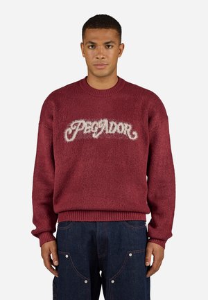Burgundy sweater with fuzzy texture and ribbed cuffs, featuring "Pegador" logo in fluffy white lettering across the chest.