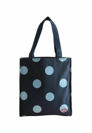 Borsa tote blu scuro con grandi pois azzurri e manici corti; presenta un'etichetta rossa con logo in basso a destra.