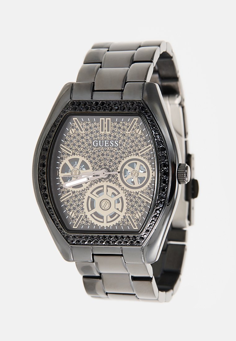 Reloj de metal negro con una caja hexagonal, esfera transparente que revela los engranajes mecánicos y una pulsera de eslabones de metal. Acentuado con cristales negros.