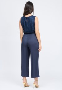 Tuta blu navy con un top strutturato e a fantasia e pantaloni a gamba larga. Presenta una scollatura a goccia sul retro e una vita elastica.