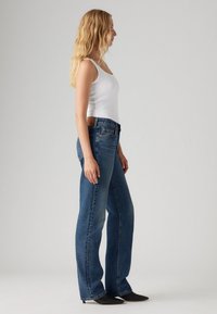 Hoge taille blauwe spijkerbroek met een rechte pasvorm, voorzien van een leren logolabel op de achterkant van de tailleband en subtiele vervaging op de stof.