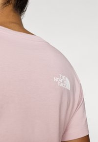 Ροζ ανοιχτόχρωμο κοντομάνικο t-shirt από βαμβάκι, με λευκό λογότυπο "The North Face" στον δεξί ώμο και στρογγυλή λαιμόκοψη.
