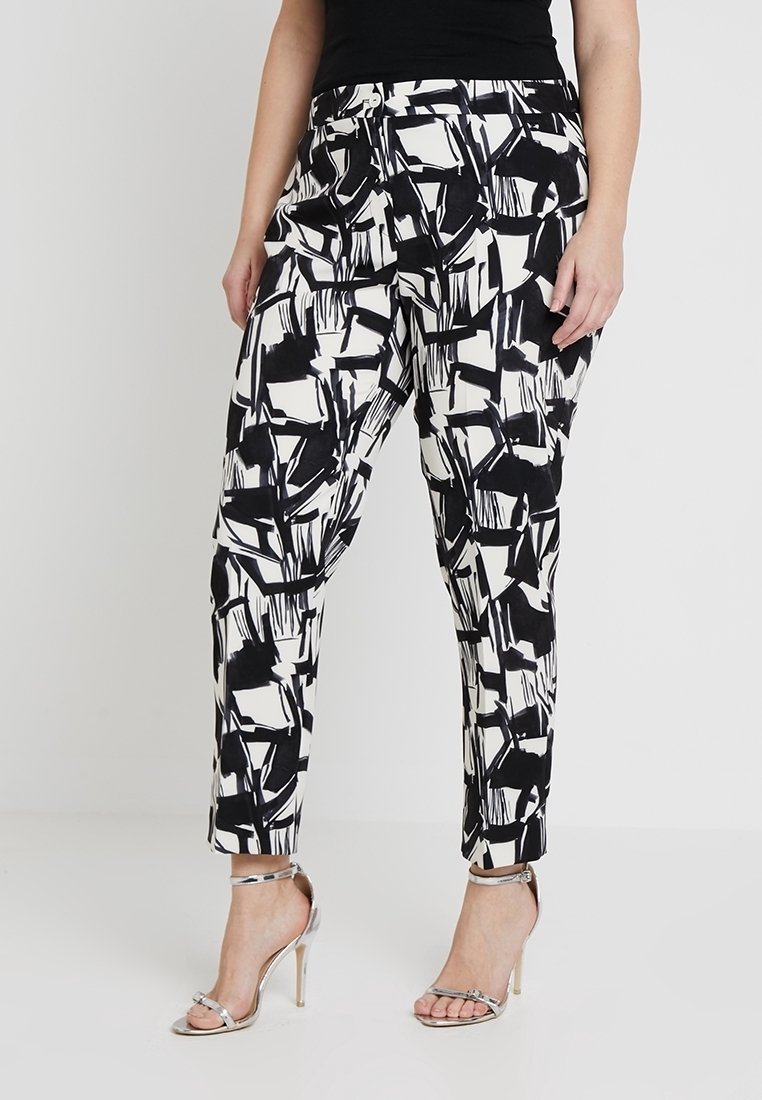 Kalhoty s černobílým vzorem a přiléhavým střihem, vyrobené z lehkého materiálu. Obsahují zip a knoflík, a mají zúžené nohavice.