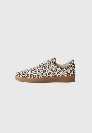 Sneaker leopardikuosi, jossa on teksturoitu turkis päällinen, pyöreä kärki, valkoiset nauhat ja ruskea kumipohja. Alle on suunniteltu perinteinen matala malli.