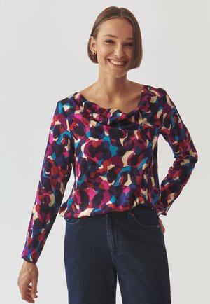 Cowl-neck, long-sleeve blouse in a vibrant, abstract pattern of pink, purple, and teal on a dark background. Smooth fabric texture.