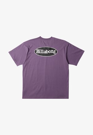 T-shirt en coton violet avec un grand logo ovale noir comportant "Billabong" en texte blanc au dos. Manches courtes et coupe décontractée.