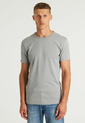 Grijs T-shirt met korte mouwen van ribstof, met een ronde hals en een subtiel logo op de borst, gecombineerd met lichtblauwe spijkerbroek.