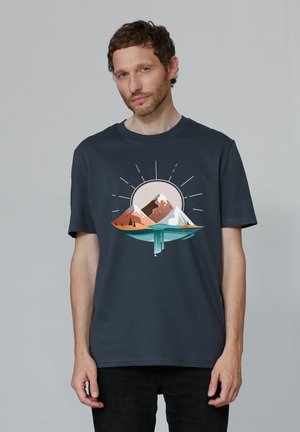 Donkerblauwe katoenen t-shirt met een grafisch ontwerp van bergen en een zon in zachte tinten bruin, wit en turquoise. Ronde hals.