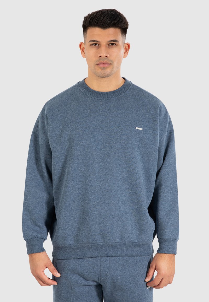 Blaues Sweatshirt aus weichem Material mit Rundhalsausschnitt, langen Ärmeln und gerippten Bündchen sowie Saum. Kleines Logo auf der linken Brust.