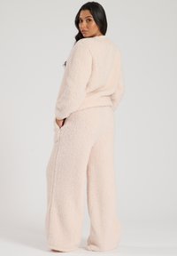 Light pink fleece loungewear set. The top features a round neckline and long sleeves, while the wide-leg pants have side pockets.