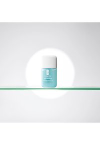 Clinique Acne Solutions Advanced Clearing Gel i en klar, lyseblå beholder med en hvit kork på en glasshylde, opplyst mot en hvit bakgrunn.
