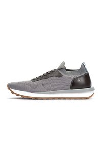 Zapatilla atlética gris de punto con acentos de cuero marrón oscuro, una entresuela blanca y una suela de goma texturizada. Presenta cordones negros y una lengüeta.