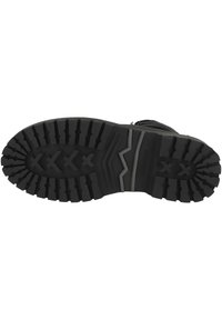 Suela de bota de goma negra con surcos profundos y agresivos, que presenta un patrón en zigzag y la palabra "DOCKERS" grabada en el lateral.
