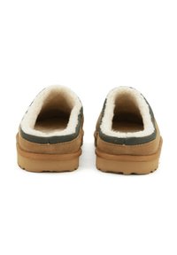 Scarpe slip-on in suede marrone con morbida fodera bianca e dettagli verdi. Presentano una suola in gomma texturizzata e un colletto imbottito per il comfort.