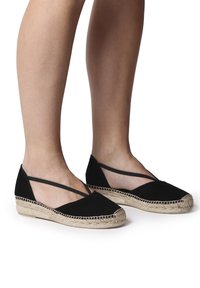 Mustat espadrille-tasapohjaiset kengät, joissa on pehmeä kangasosa, joustavat ristiviillot ja juuttiin kääritty pohja. Tyylikäs muotoilu, jossa on pyöristetty varvas.