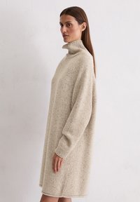 Beiges Strick-Turtleneck-Kleid mit lockerer Passform, langen Ärmeln und gerippten Bündchen. Verfügt über ein strukturiertes Muster. 