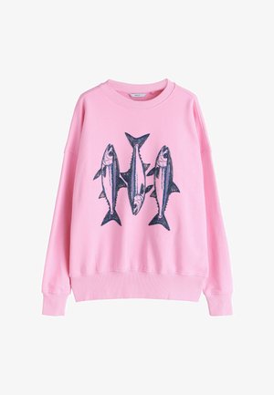 Różowa bluza z nadrukiem trzech granatowych ryb na przodzie. Ma okrągły dekolt oraz ściągacze na rękawach i dole. Miękka tekstura materiału.