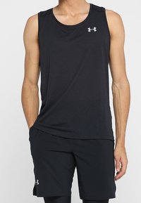 Débardeur de sport noir en tissu léger, avec un col rond et un logo discret sur la poitrine. Associé à un short noir.