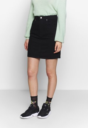 Black denim skirt with a fitted design, featuring a high waist, front pockets, and a single button closure. Worn with black sneakers and floral socks.