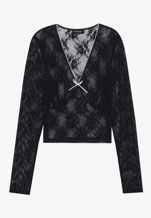 Svart blond langermet topp med dyp V-hals som har blomstermønster og en hvit sløyfe i midten. Kuttet design.