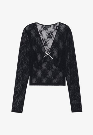 Black lace long-sleeve top with a deep V-neckline, featuring floral patterns and a white bow accent at the center. Cropped design.