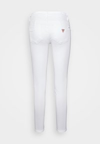 Jeans blancos ajustados con una textura suave, diseño de cinco bolsillos y un pequeño parche con el logo en la parte trasera. Cuenta con una cinturilla de altura media.