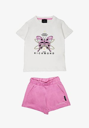 T-shirt bianco in cotone con una grafica di farfalla rosa e testo nero, abbinato a pantaloni corti rosa con vita elastica e tasche.