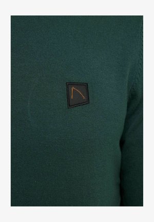 Suéter de punto verde oscuro con un pequeño parche de logo negro y naranja en el área del pecho izquierdo. Textura suave con un diseño ajustado.