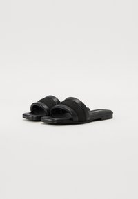 Black slide sandals featuring two thick straps and a flat sole. Made from synthetic materials with a smooth texture. Minimalist design.