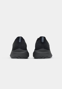 Black athletic shoes with a textured fabric upper, rounded heel, and a thick, molded rubber sole. Features a pull tab at the back.