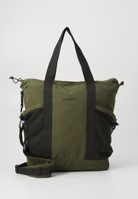 Sac fourre-tout vert olive en tissu avec des sangles en toile noires, poches latérales en maille et une bandoulière réglable. Équipé d'un logo sur le devant.