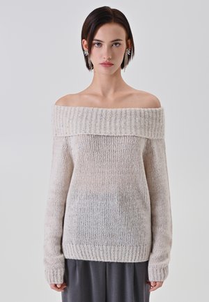 Maglione lavorato a maglia di colore bianco sporco, con scollo a barca e collo a coste spesso, maniche lunghe e vestibilità morbida e leggermente ampia, con una texture evidente.
