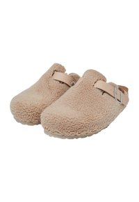 Sabots beiges en shearling avec un dos ouvert, semelle plate et sangle en cuir léger. Surface texturée avec un aspect doux et duveteux.