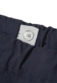 Marine stoffen tailleband met een wit label en een doorzichtige knoopsluiting; zichtbaar stiksel en textuur van het materiaal.