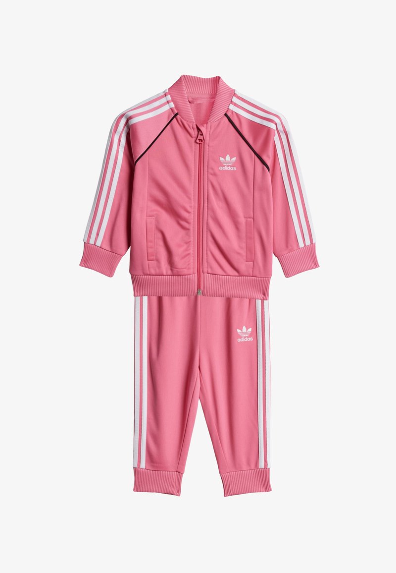 Pink polyester tracksuit with a zip-up jacket featuring white stripes and logo, paired with matching pants, both having ribbed cuffs.
