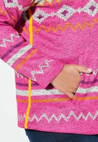 Fleecejacke in lebhaftem Pink mit bunten Zickzack- und Diamantmustern. Verfügt über eine versteckte Tasche und kontrastierende gelbe Reißverschlussschließe.