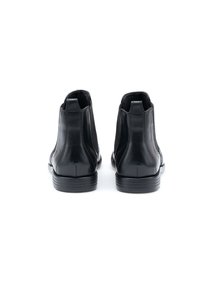 Zwarte leren enkellaarsjes met een slank design, voorzien van elastische zijpanelen en een gestructureerde zool voor grip. Gladde afwerking met subtiele stiksels.