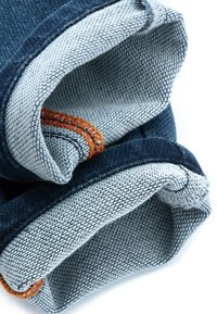 Cuffie di jeans in denim di un blu intenso con una fodera interna grigia. Presentano dettagli cuciti arancioni e una texture sfrangiata lungo i bordi.