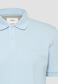 Polo a maniche corte di colore azzurro chiaro con due bottoni e colletto, con un ricamo discreto del marchio s.Oliver sul petto.