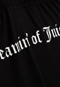 Tessuto nero con testo bianco che legge "Meanin' of Juice" in un carattere audace e angolare. Il materiale appare liscio con una leggera lucentezza.