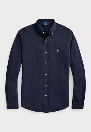 Mörkblå skjorta med knappar, tillverkad av mjukt tyg, med klassisk krage, långa ärmar och en liten broderad logotyp på bröstet.