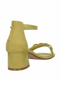 Sandali con tacco in suede giallo, con tacco a blocco rotondo, cinturino alla caviglia e dettaglio a loop decorativo sulla fascetta anteriore. Texture liscia.