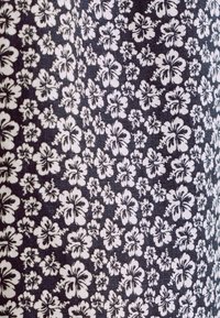 Marine stof met een klein wit bloemenpatroon. Het ontwerp bevat talrijke hibisco-achtige bloemen en delicate blaadjesaccenten. Textielstructuur zichtbaar.