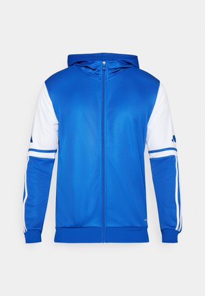 Chaqueta deportiva azul con cremallera y capucha, con detalles en blanco en las mangas y el hombro, hecha de un tejido suave y ligero.